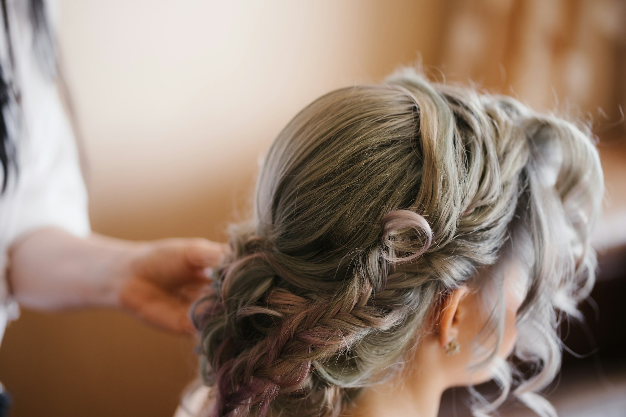 Stylist makes the bride a beautiful hairstyle. Side view